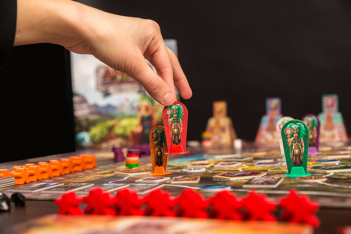 A player lifting a Mayan leader meeple mid-game